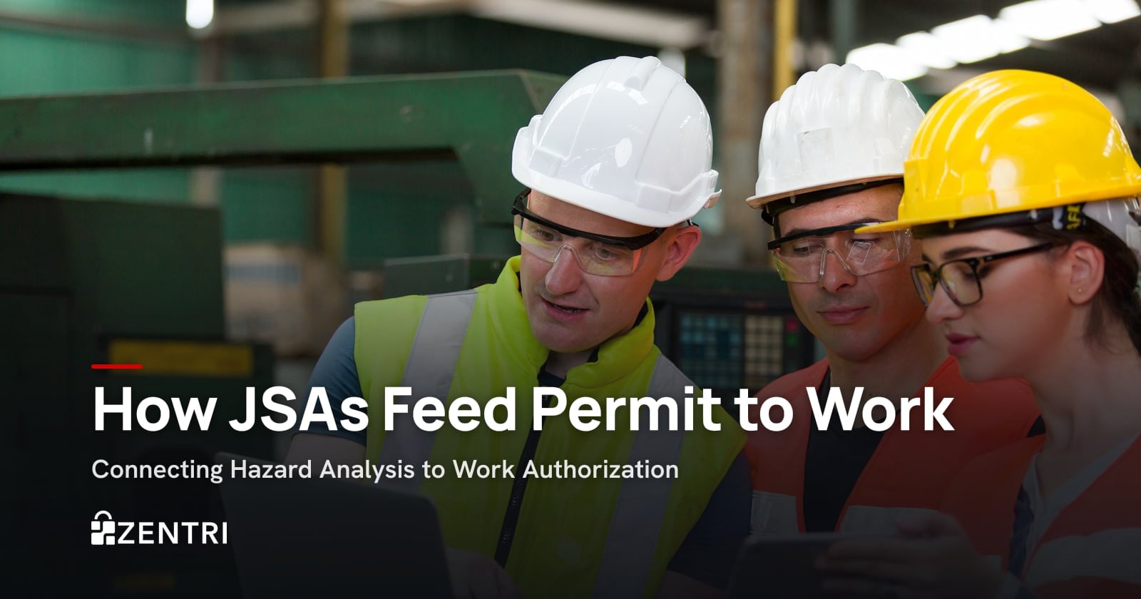 Factory workers in hard hats and safety glasses reviewing a laptop together