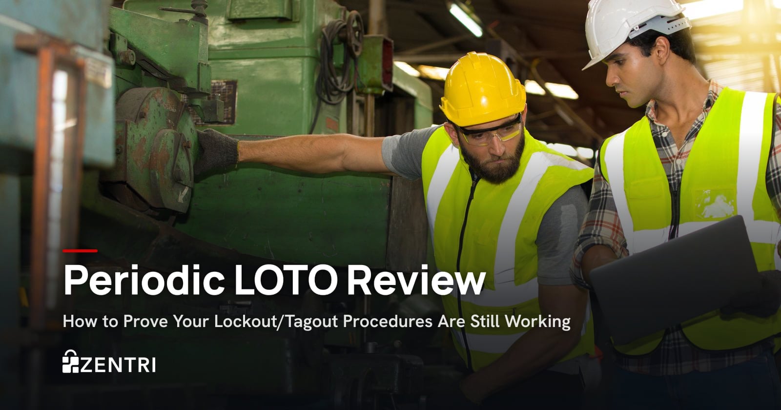 Two engineers in hard hats inspecting factory machinery with a laptop