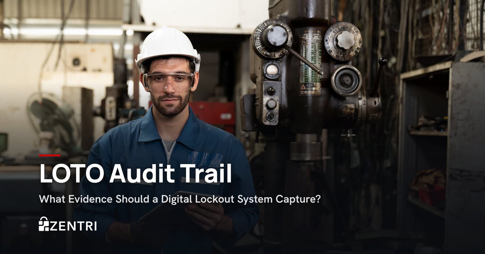 Engineer in a hard hat and safety glasses standing by factory machinery